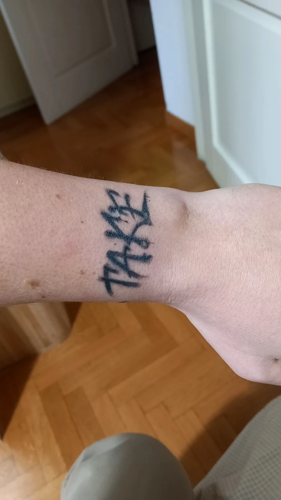 Polso con tatuaggio visibile con scritta stilizzata nera, ambiente domestico, proveniente da studio Sailors Tattoo a Milano.